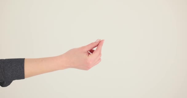 女性の手はベージュの壁に対してお金を求めるジェスチャーを示す 手ともにヌードマニキュアヒントの取得お金として支払スローモーション — ストック動画