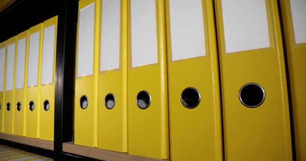 黄色のフォルダは オフィスの敷地内のラックの棚に長蛇の列に入れます 会計資料と仕事のための報告書と文書リングバインダーの組織構造 — ストック動画