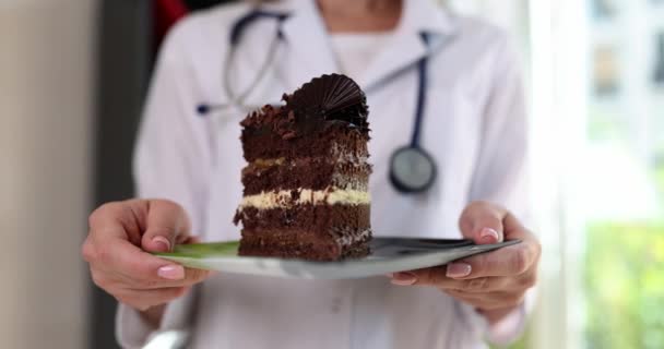 의사는 초콜릿 케이크 조각이 접시를 청진기를 가운을 여인은 창문에 대하여 — 비디오