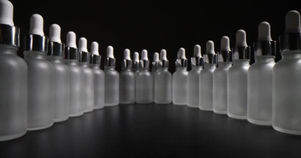 円の中に配置されたピペット付きの空のボトルの数が多い 化粧品や医薬品の保管を目的としたピペット付きボトルが黒い表面に立っています — ストック動画