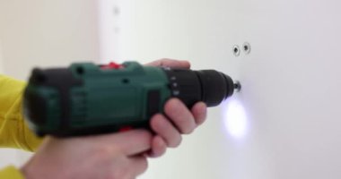 İşçi, yenilenmiş odada elektrikli tornavidayla vidaları söküyor. Becerikli inşaatçı ev sahiplerinin yavaş çekimde tamirat yapıyor.