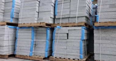Depodaki paletlerin üzerindeki granit levhalar. Duvarları ve zemini tamamlamak için inşaat malzemeleri. Binaların iç ve dış tasarımı için dayanıklı malzeme