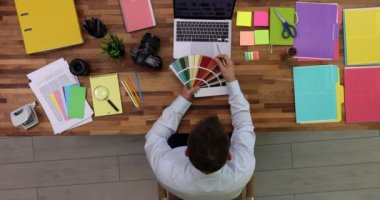 Stüdyo üst görüntüsü 4K filminde dizüstü bilgisayarın yanında renk seçen tasarımcı. İç tasarım hizmetleri kavramı