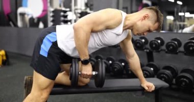 Kol bilekliğinde spor bilekliği olan bir sporcu ağırlık kaldırıyor ve spor salonu 4K filminde ağır çekimde pazılarını çalıştırıyor. Spor konsepti sırasında düzgün nefes almak