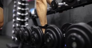 Spor eğitimi için spor salonundaki halterli erkek sporcu ağır çekimde 4K film izliyor. Sağlıklı yaşam tarzı kavramı