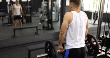 Spor salonundaki halteri kaldıran sporcu ağır çekimde. Güç yükü kol kasları kavramına