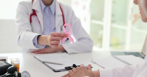 Врач Маммолог Держит Розовую Ленту Передает Пожилой Женщине Клинике Международный — стоковое видео