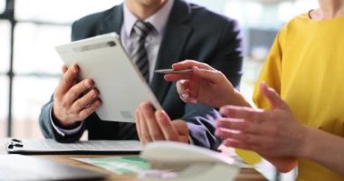 Dijital tablet kullanarak konuşan iş arkadaşları ofis masasında oturuyorlar. Teknik cihaz ve kurumsal teknoloji iş uygulamaları