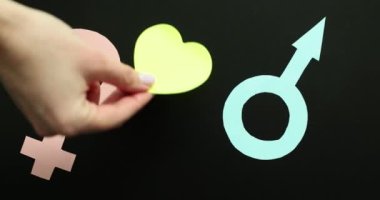 Siyah arka planda kadın ve erkek ikonu arasındaki kağıt kalp. Erkek ve kadın arasındaki ilişkiler ve romantik duygular.