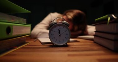 Gece geç saatlerde ofiste çalar saatle masada uyuyan bir iş kadını. Fazla mesai ve fazla mesai