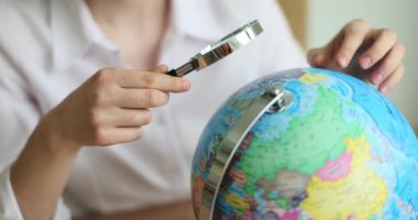 Turist büyüteçle dünya küresine bakıyor. Dünya turizmi ve egzotik yerler arayışı
