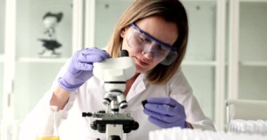 Bilim adamı mikroskop camına kozmetik yağı damlatıyor. Kozmetik ürünleri araştırması