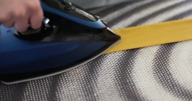 Kadın kadın eteğinin kemerini demirle ütülüyor. Kumaş bandı ya da kravat ütüleniyor