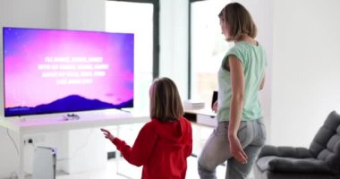 Modern oyun konsolu olan bir anneyle kızının aktif aile dansları. Projektör kullanan aile oyunları