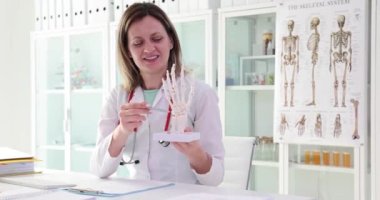 Doktor el iskeleti modelini elinde tutuyor. Klinikte ellerin iskeleti üzerine çalışma