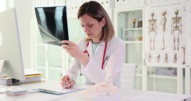 Doktor kırık ayaklı röntgene bakıyor. Kaza sigortası kavramı