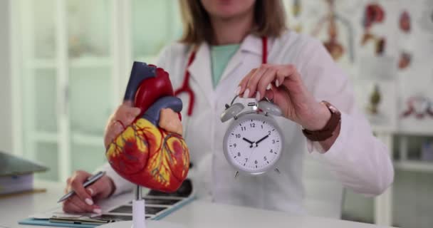 心臓科医は診療所で心臓の目覚まし時計モデルを持っています 臓器の解剖学的構造と寿命 — ストック動画