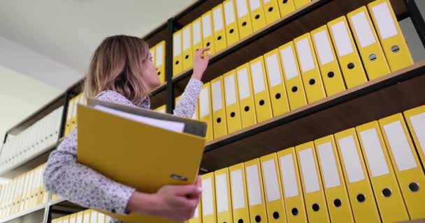 会計従業員は上棚からの書類のための会計資料と黄色のフォルダを取る 保管及び事業文書 — ストック動画
