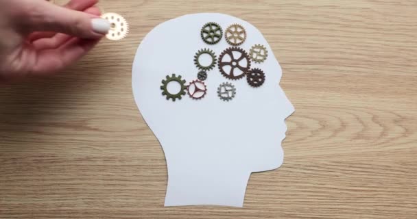 歯車の脳と手は紙の頭の上に多くの歯車パズルを置きます 精神的な仕事の概念 — ストック動画