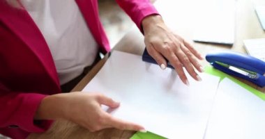 Sekreterin elleri ofiste yumruklayıcı ile evraklarda delikler açıyor. Kırtasiye konsepti