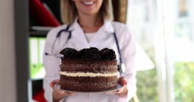 Beslenme uzmanı doktor elinde çikolatalı pasta tutuyor. Düzgün beslenme ve sağlığa zararlı tatlılar