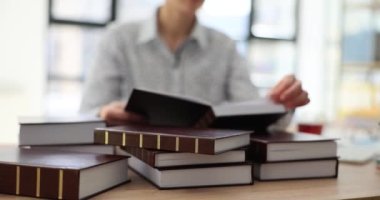 Kadın çalışan, ofisteki ahşap masada oturan ekonomi araştırmaları için kitap sayfalarını çeviriyor. İş kadını ticari yavaş çekim dizininde bilgi istiyor