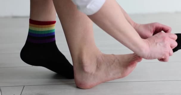 Man Trekt Zwarte Sokken Aan Met Regenboog Veelkleurige Strepen Legt — Stockvideo