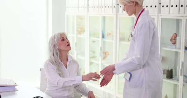 Θετική Ξανθιά Γιατρός Στολή Σφίγγει Χέρι Χαμογελώντας Ώριμη Γυναίκα Ασθενή — Αρχείο Βίντεο