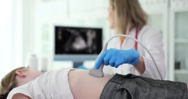 İlgili doktor küçük kızın midesini modern ultrason cihazıyla kontrol ediyor. Kadın yavaş çekimde ekrana bakarken tıbbi ekipman kullanıyor.
