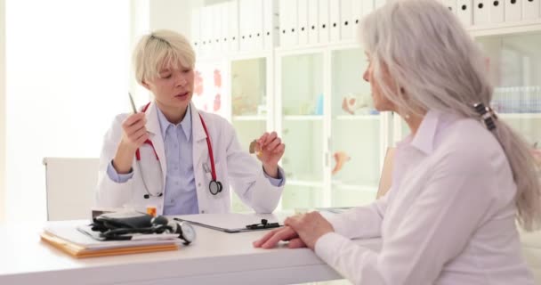 Kobieta Lekarz Wyjaśnia Prawidłowe Wykorzystanie Aparatu Słuchowego Dojrzałego Klienta Kobieta — Wideo stockowe