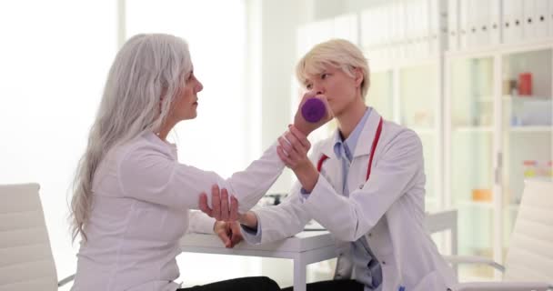 Vrouwelijke Arts Helpt Oudere Vrouwelijke Patiënt Elleboog Buigen Kliniek Premise — Stockvideo