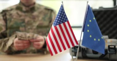 Amerikan ve Avrupa Birliği, askeri subaya karşı uluslararası yardım olarak para sayıyor. Askeri üniformalı adam ofiste ağır çekimde oturuyor.