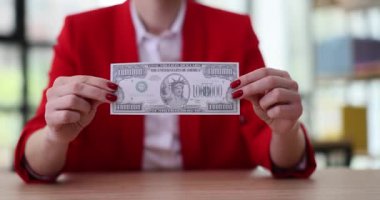 Kırmızı ceketli kadın milyon dolarlık banknot tutuyor. Başarılı bir iş kadını, ofisteki ahşap masada oturup banknotlara bakar. Finansal başarı