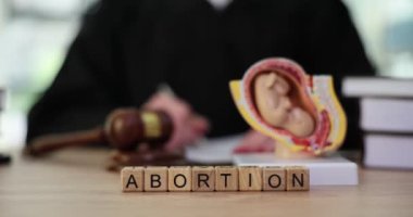 Yargıç masasında tahta küplerle kürtaj sözü. Yargıç fetal modelin yanında dava açmak için notlar alır. Kürtaja karşı yasayı yavaş çekimde kabul et