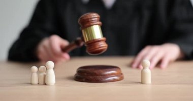 Kadın yargıç, tokmağı masada küçük tahta figürlerle yere serdi. Çocuklu ailelerin ayrılması ve adaletin yeniden sağlanması. Mahkemede ağır çekimde boşanma