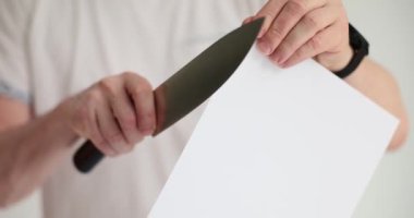 Erkek adam, kağıt levhayı keskin bir bıçakla kesiyor. Personel mutfak aletlerinin yavaş çekimde et kesme reklamını yapıyor.