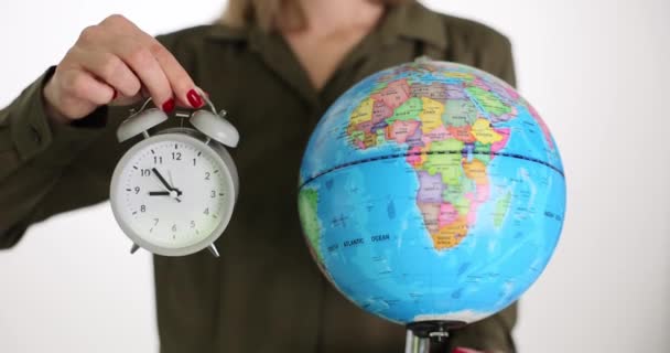 赤いマニキュアを持つ女性は ヴィンテージ目覚まし時計と地球を示すスタンド 女教師は地理を勉強する時間を測る 世界中を旅するのに最適な時期 — ストック動画