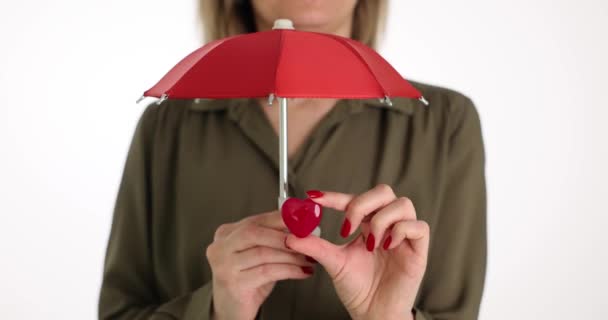 女人的手在红色的伞下握住小心形 微笑的女性渴望保持善良和人性 人表现出爱心和爱心 — 图库视频影像