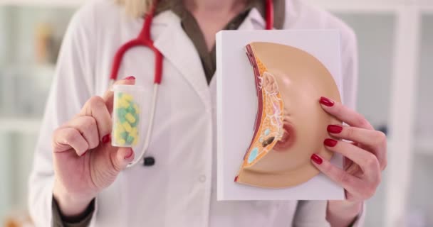 医生手里拿着药丸 手里拿着女性乳房和奶瓶的人造模型 专家开出治疗乳腺疾病的药方 — 图库视频影像