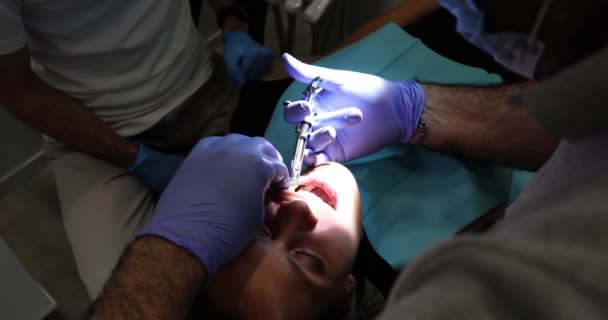 Dentysta Robi Anestezjologiczny Ukłucie Strzykawką Ustach Pacjenta Oświetlając Światłem Lekarz — Wideo stockowe
