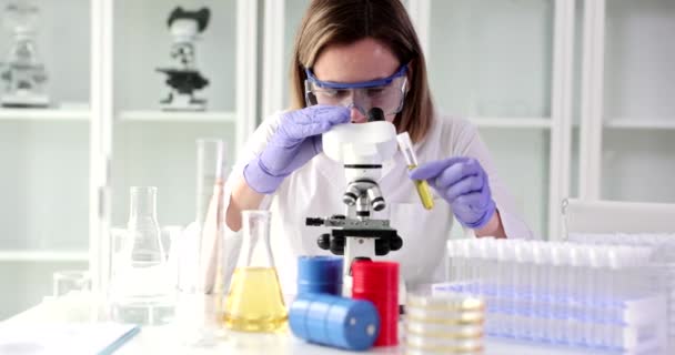 Mulher Química Ajusta Microscópio Segurando Tubo Com Líquido Amarelo Mão — Vídeo de Stock
