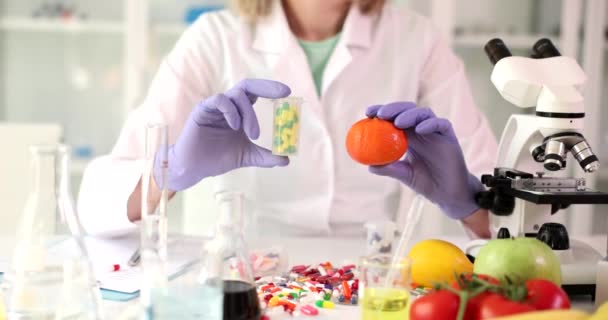 Kobieta Chemik Gumowych Rękawiczkach Trzyma Paczkę Pigułek Świeżą Organiczną Mandarynkę — Wideo stockowe