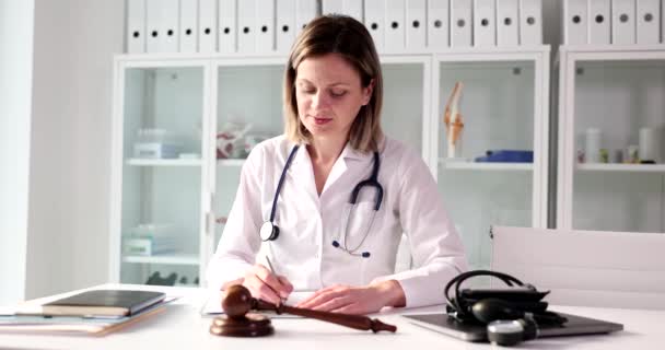 Woman Doctor Work Uniform Writes Notes Next Gavel Distracting Patient — Stock Video