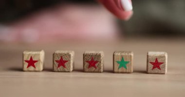 Kadın parmağı, yeşil yıldızlı tahta küpü, bulanık arkaplanda kırmızı desenli bloklara doğru hareket ettirir. Liderlik kavramı