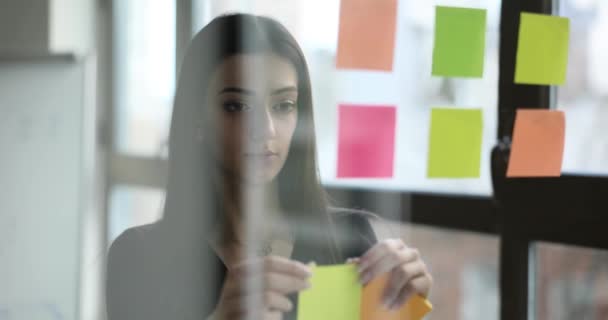 Mitarbeiterinnen Kleben Aufkleber Mit Wichtigen Arbeitsplänen Auf Glasplatten Firmenräumen Brünette — Stockvideo