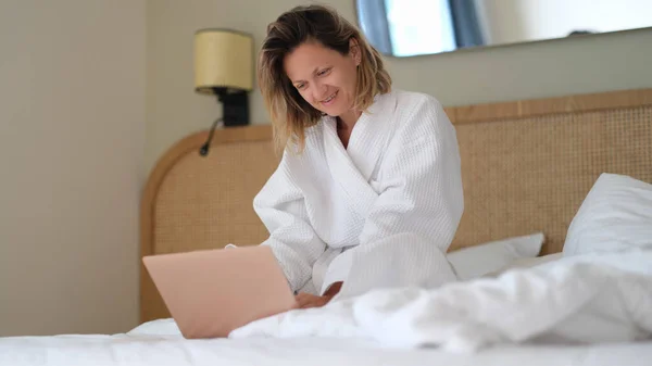 Молода Жінка Білому Халаті Працює Дистанційно Ноутбуком Ліжку Вдома Телевізійна — стокове фото