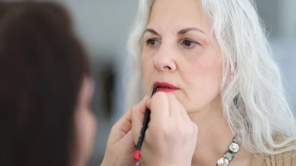 Kosmetolog Malujący Usta Czerwoną Szminką Starszej Kobiecie Makijaż Dla Każdej — Zdjęcie stockowe