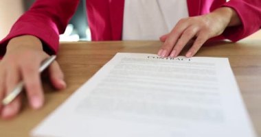 Kadın yönetici, sözleşme belgelerini kalemle imzalamak için partner teklif ediyor. Kadın masada oturuyor ve ağır çekimde kârlı bir anlaşma yapmaya hazır.