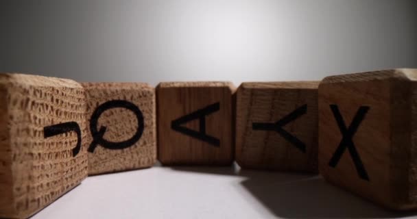 白いテーブルの上に曲線状に配置された英語の文字を持つ木製のキューブ グレーの背景ズームアウトでゲームを開発するための木材で作られたキッズブロック — ストック動画