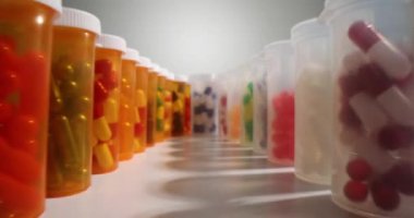 Beyaz masanın üzerinde duran çeşitli haplar ve vitamin kapsülleriyle şeffaf plastik şişelerin önünden geç. Sağlık ve organ için etkili ilaç